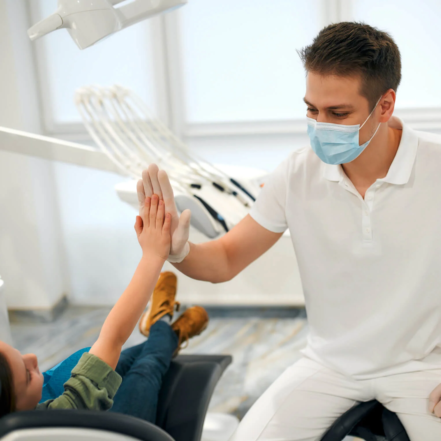 Ein Zahnarzt gibt einer jungen Patientin ein High Five Ein Zahnarzt gibt einer jungen Patientin ein High Five
